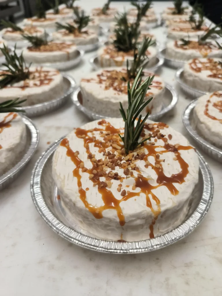 Photo d'un camembert cuit au barbecue, parsemé de pralin, romarin, miel et caramel au beurre salé.